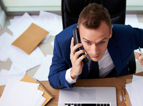 Homme stressé en train de gérer 36 tâches à la fois, bureau encombré avec dossiers, symbole de surcharge mentale et de manque d'organisation